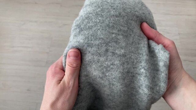 A woman checks the density of a wool sweater. A woman's hands stroke a soft, warm cloth. Warm clothes are the only way to stay comfortable and protect yourself from the cold