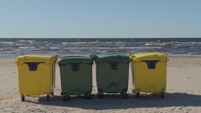 Industrial bins on serene seaside landscape. Quiet beach with colorful waste bins during off season