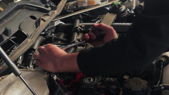 Odijk, Netherlands, May 2, 2026. Car mechanic uses torque wrench to loosen ignition coils . Close up of hands