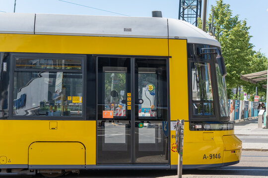 Germany, Berlin May 25, 2026 A close side view shows yellow BVG tram doors and windows in Berlin. Reflections, rails and nearby trees add urban transport detail.