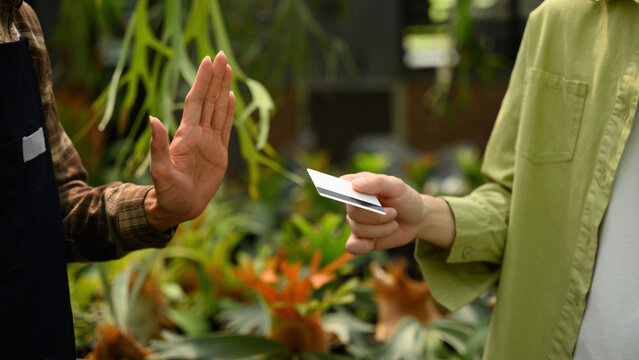 Cropped Shot of Shop Owner Refusing Credit Card Payment from Customer in Plant Nursery Store