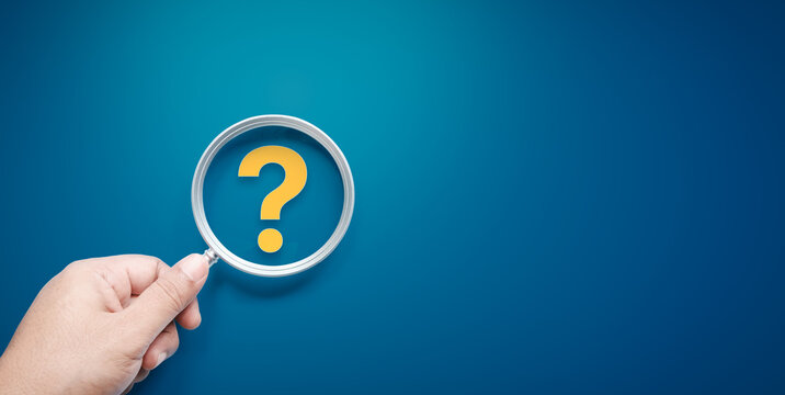 Hand holding silver magnifying glass focus on yellow question mark, premium gradient blue background, International ask a question day concept, Answer, Q&A, Communication and Brainstorming