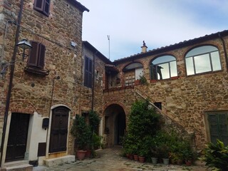 Fototapeta premium Patio tradicional de piedra con escalera exterior y plantas en el pueblo medieval de Montemerano, Toscana, Italia.