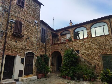Patio tradicional de piedra con escalera exterior y plantas en el pueblo medieval de Montemerano, Toscana, Italia.