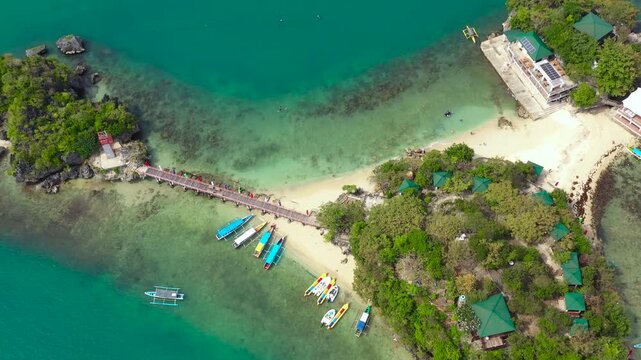Aerial view: Tropical Island with a beautiful beach and vacationing tourists, tourist boats. Quezon Island Beach, Hundred Islands National Park, Pangasinan, Philippines. Alaminos. Summer and travel