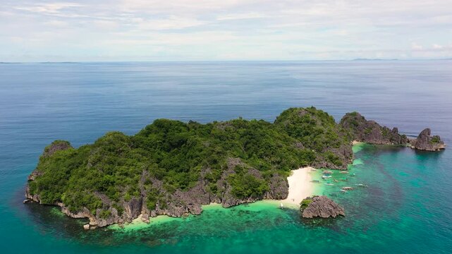Beautiful tropical beach with tourists and boats, aerial drone. MatukadIsland, Caramoan Islands, Philippines. Summer and travel vacation concept. Tropical island with a white sandy beach.