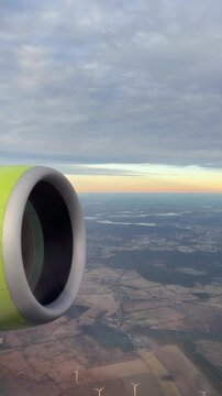 Brandenburg landscape viewed from airplane during overcast winter morning with lime green jet engine in frame, patchwork fields and lakes, low cloud cover and soft light conveying quiet aerial travel