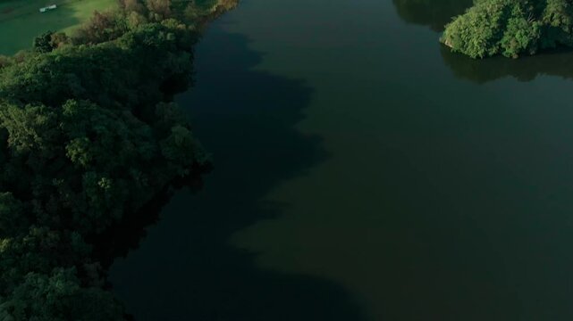 Calm dark waters of Laguna La Mar&iacute;a surrounded by tropical forest and rolling mountains in Colima, Mexico. Top down view to tilt up reveal shot