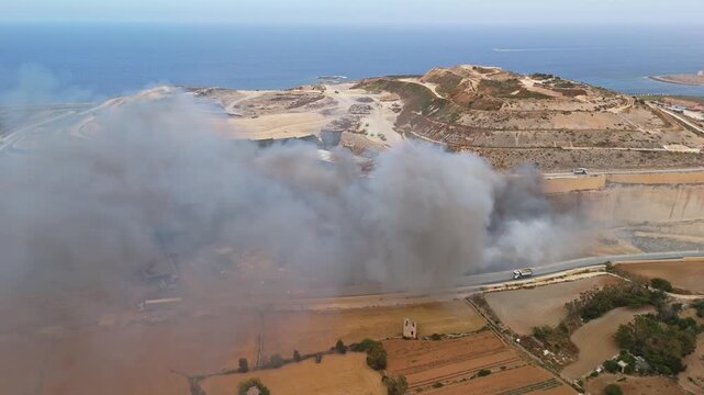 In Magħtab, Malta, a landfill fire sends thick, dense toxic smoke over waste piles as firefighters respond to the hazardous incident in a static aerial view on May 6th, 2026.