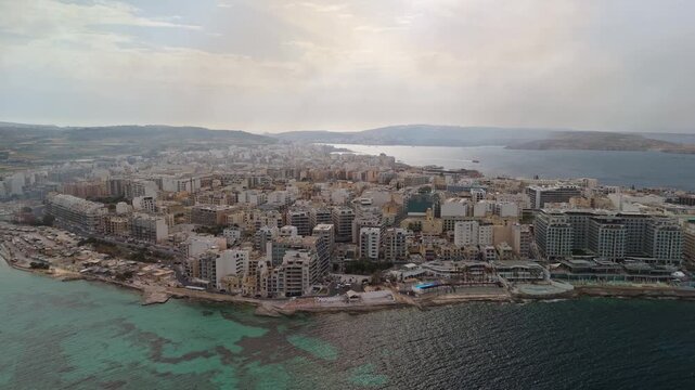 In Malta, drone footage shows smoke from the Magħtab landfill fire spreading over Qawra, Buġibba and St Paul&rsquo;s Bay, covering the coastal urban landscape along the Mediterranean shore on May 6th, 2026.