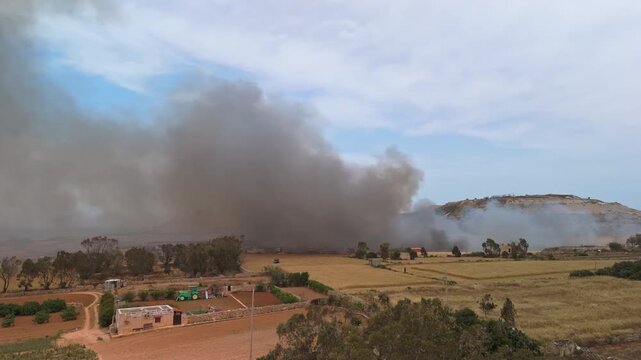 In Maghtab, Malta, an active waste-site fire sends thick toxic smoke over the surrounding landscape and local farmhouses in this aerial view on May 6th, 2026.