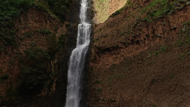 Immersive close up backward aerial of El Salto del Nogal waterfall amist rocky cliffs in Tapalpa, Mexico