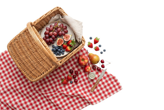 Picnic basket with fruits on red checkered cloth