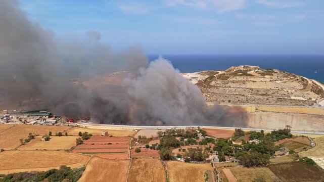 At Maghtab in Malta, a landfill fire sends toxic smoke over the industrial area as firefighters and response vehicles operate around the waste site in a drone view on May 6th, 2026.