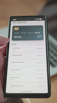 Hand holding a smartphone with a fintech mobile app showing high account balance and cash flow. Passive income