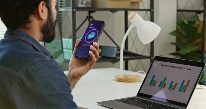 Businessman using a voice command features talking to a virtual AI assistant while working on a laptop at office. Speech recognition, Smart business entrepreneur technology and mobile automation.