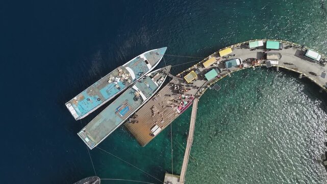 Aerial view of Portree town with colourful houses and fishing boats in Indonesia. Scenic view of the natural harbour and port by high ground and cliffs. Popular tourist destination on the Wakatobi Isl