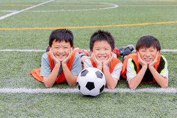Naklejka premium サッカーボールを囲んで笑顔を見せる少年チーム