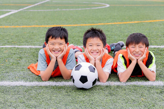 サッカーボールを囲んで笑顔を見せる少年チーム