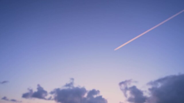 朝焼けの美しいグラデーションの空を一直線に進む飛行機雲