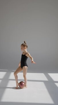 Little gymnast posing with a ball on a white background. 
