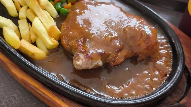 Sizzling chicken steak freshly cooked on a hot stone plate with natural steam vapor smoke macro shot for restaurant menu promotion and culinary commercial advertising