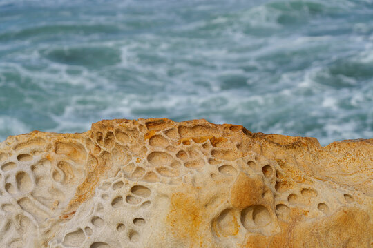 Tafoni rock formation on sea coast with ocean waves. Yamba Breakwater, New South Wales, Australia 