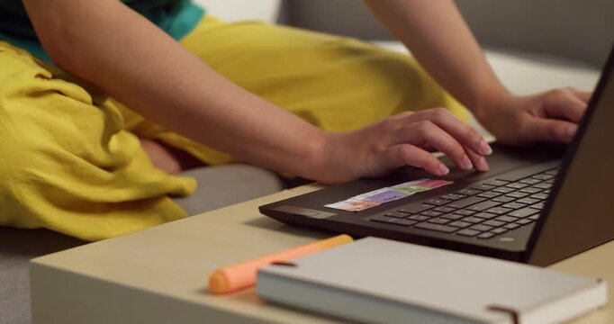 A close-up of hands typing a laptop in a cozy home office setting.