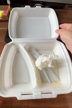 Hand closing a white styrofoam takeaway food container