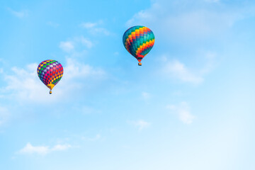 Naklejka premium Rainbow colored hot air balloons flying in the sky at sunset. The blue sky with white clouds in the background