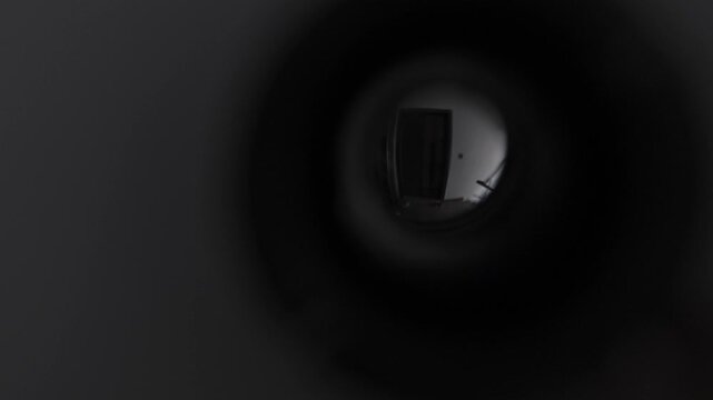 POV persecution mania and paranoia concept looking through door peephole, anxious perspective of apartment corridor, psychological fear and suspense