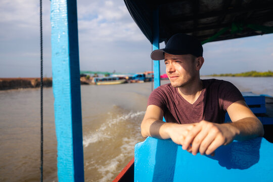 Tourist in boat exploring traditional floating village on Tonle Sap lake in Cambodia. Southeast Asia travel, local lifestyle, community culture, water transport and tourism concept.