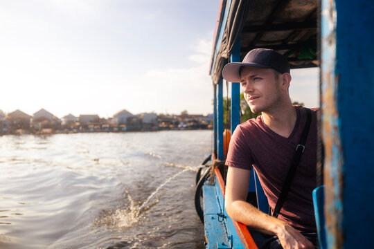 Tourist in boat exploring traditional floating village on Tonle Sap lake in Cambodia. Southeast Asia travel, local lifestyle, community culture, water transport and tourism concept.