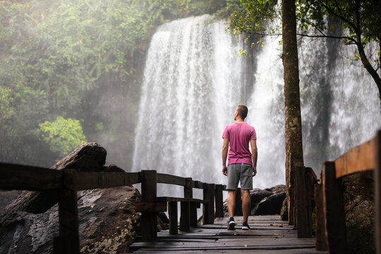 Tourist walking to big Phnom Kulen waterfall in Cambodia nature during adventure travel. Tropical climate, outdoor exploration, tourism and asian destination concept.