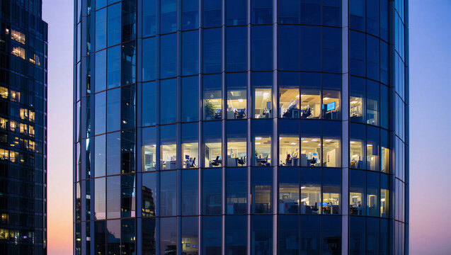 Modern glass office tower at dusk with interior lights business district building architecture