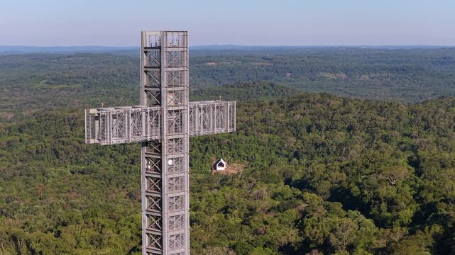 Drone close up of giant cross monument and small chapel surrounded by rainforest in Parque Tem&aacute;tico de la Cruz.