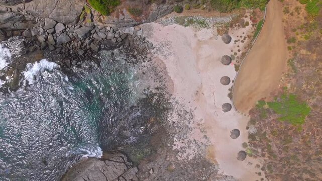 Top-down aerial view of Punta Pite Beach, a small, secluded, and exclusive beach with umbrellas made of natural materials, Papudo, Valpara&iacute;so