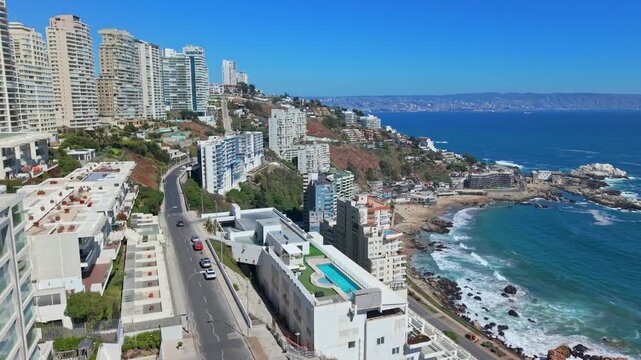 Aerial view dolly in of luxury residential condos with a pool in Concon, Chile, overlooking the ocean on a sunny day