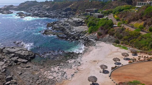 Panoramic aerial view of Punta Pite Beach in Papudo, Valpara&iacute;so, with natural parasols and exclusive luxury mansions on a sunny day
