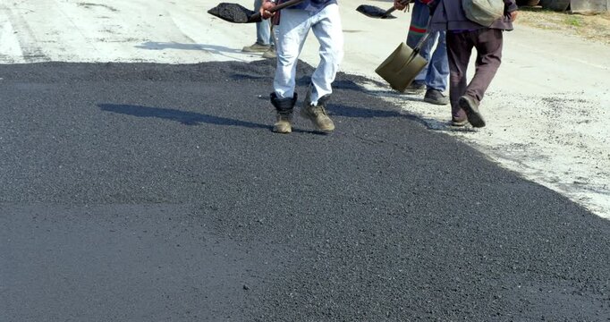 Workers are busy laying asphalt road showcasing teamwork and dedication.