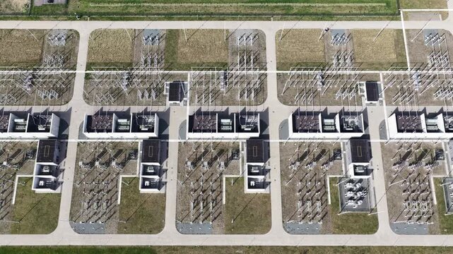 High voltage electrical substation with transformers and power lines seen from drone top down, showcasing grid infrastructure, transmission equipment and industrial energy distribution facility