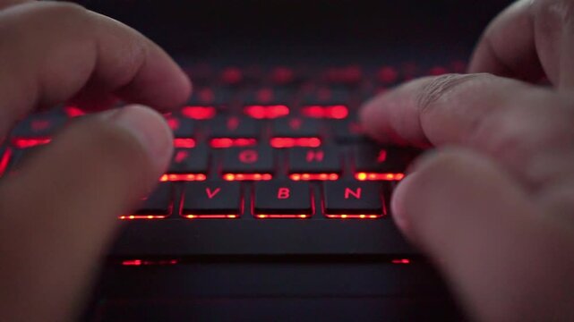 hands typing on red backlit keyboard, digital lifestyle, programming, and computer usage.