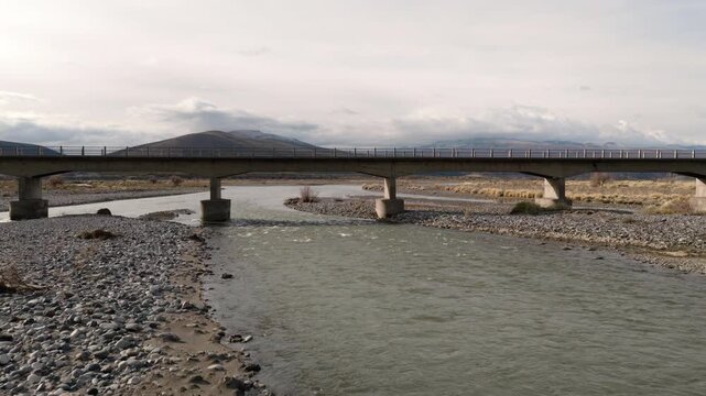 Ruta Nacional 145 bridge spans R&iacute;o Grande near Bardas Blancas in Paso Pehuenche, Mendoza Province, Argentina, drone forward flyover push in shot above braided Andean river channels.