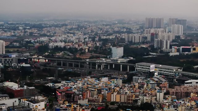 Aerial view of Electronic cityscape with buildings, flyovers, metro line, haze and moving vehicles at Bangalore, karnataka, india. day time, push in shot, drone shot, 4k.
