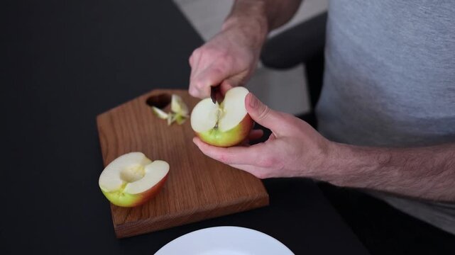 man cutting fresh red apple on wooden board at kitchen table in apartment Full HD video