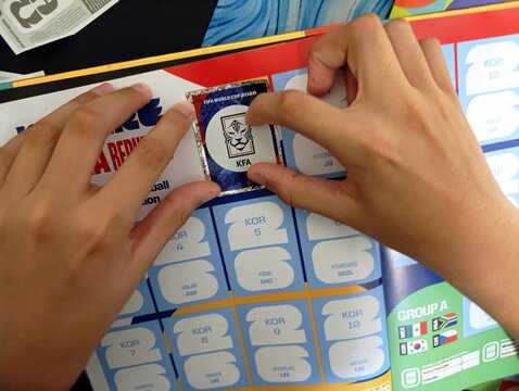 Crian&ccedil;a colando figurinhas no &aacute;lbum da Copa do Mundo - FIFA 2026 - World Cup 2026 - PANINI.