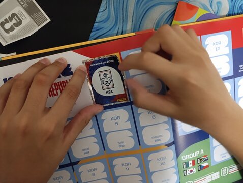 Crian&ccedil;a colando figurinhas no &aacute;lbum da Copa do Mundo - FIFA 2026 - World Cup 2026 - PANINI.
