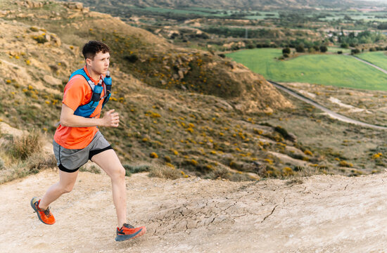 Male athlete trail running on mountain path