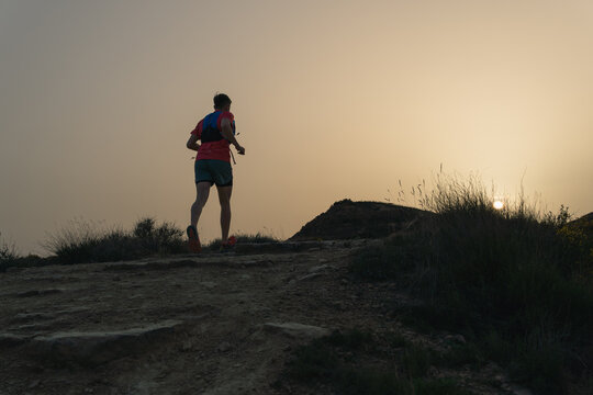 Trail runner running on mountain path at sunset
