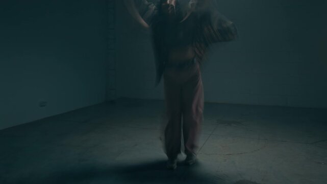 Front view wide angle shot of young woman dancing expressive hip hop freestyle under strobing lights in dark empty studio with accelerated motion blur effect, cinematic underground vibe, copy space